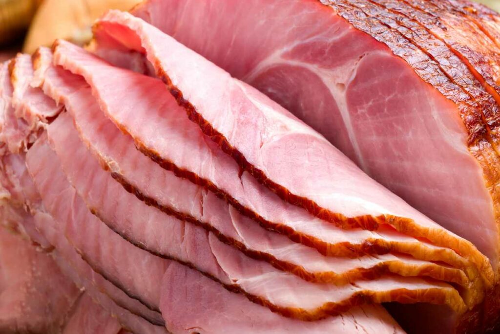 Un morceau de jambon cuit coupé en tranches.